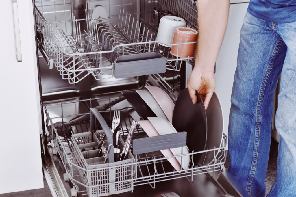 Midsection of man loading dishwasher